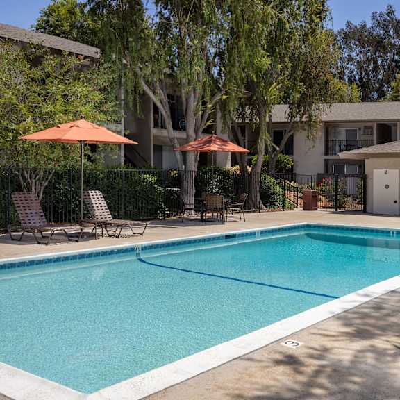 a swimming pool surrounded by chairs and umbrellas.