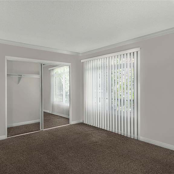a room with a carpeted floor and a window with blinds.