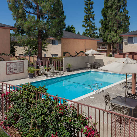 a pool surrounded by a fence and patio furniture.
