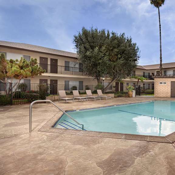 a pool surrounded by a patio and trees.
