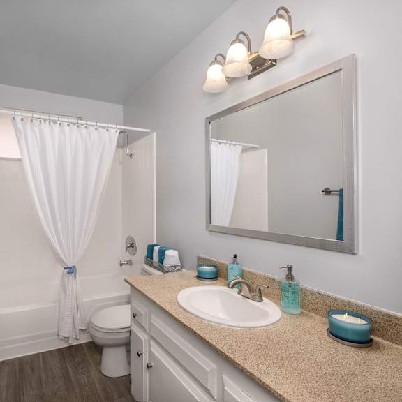 a bathroom with a toilet, sink, mirror, and a blue towel.