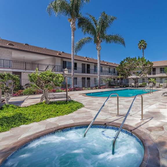 a pool with a slide in the middle of a courtyard surrounded by palm trees.