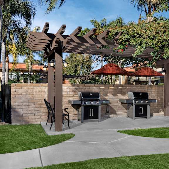 a patio with a grill and a pergola.
