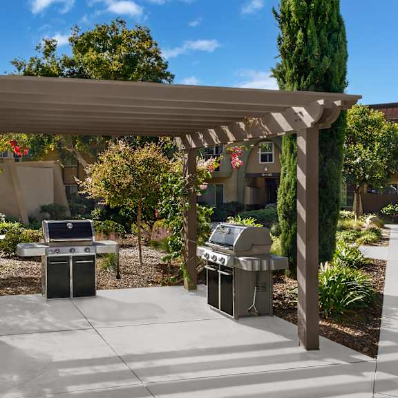 a patio with a grill and a pergola.