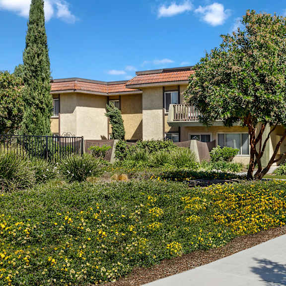 a building with a yellow flower bed in front of it.