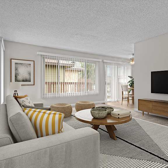 a living room with a grey couch, a coffee table, a flat screen tv, and a rug.