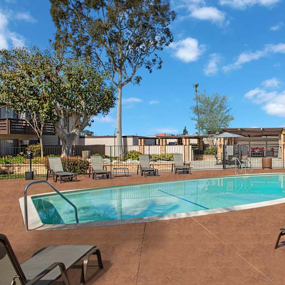 a pool surrounded by chairs and trees.