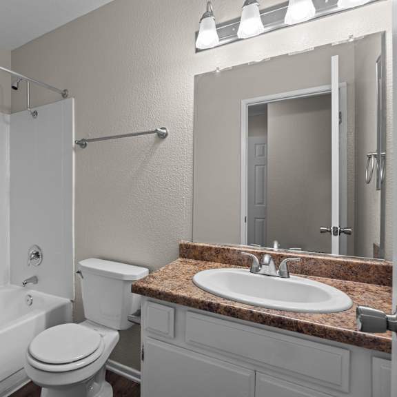 a white bathroom with a toilet, sink, and shower.