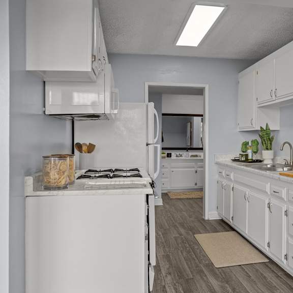 a white kitchen with a stove, oven, and cabinets.