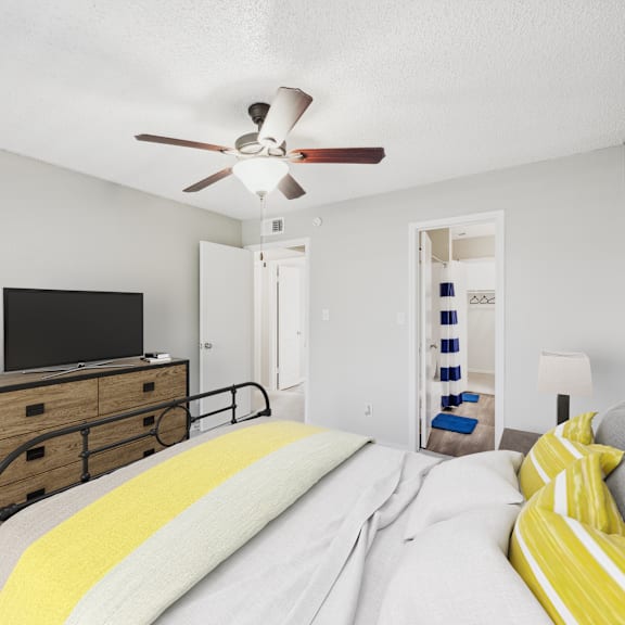 a bedroom with a bed, a dresser, and a ceiling fan.