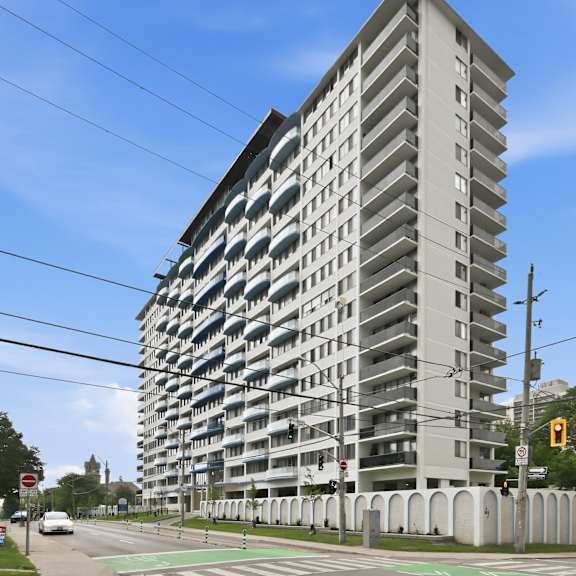 a tall residential building with a grey facade and balconies on each floor.