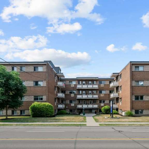 a large brick apartment building with a tree in front of it.