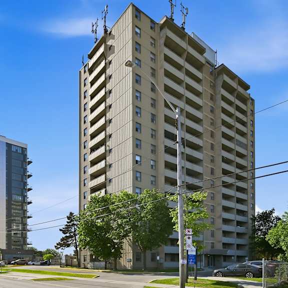 a tall building with a flat roof and a balcony on the top floor stands next to a shorter building with a curved roof.