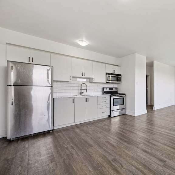 a kitchen with a refrigerator, microwave, oven, and sink.
