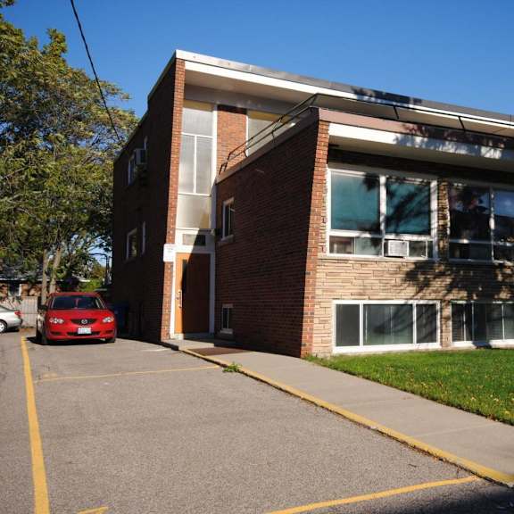 a red car is parked in a parking lot in front of a building.