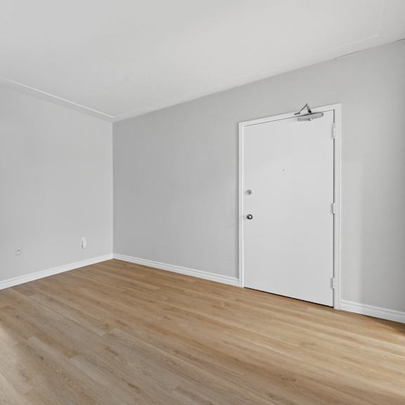 a white room with a wooden floor and a white door.