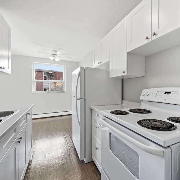 a white kitchen with a stove, sink, and refrigerator.