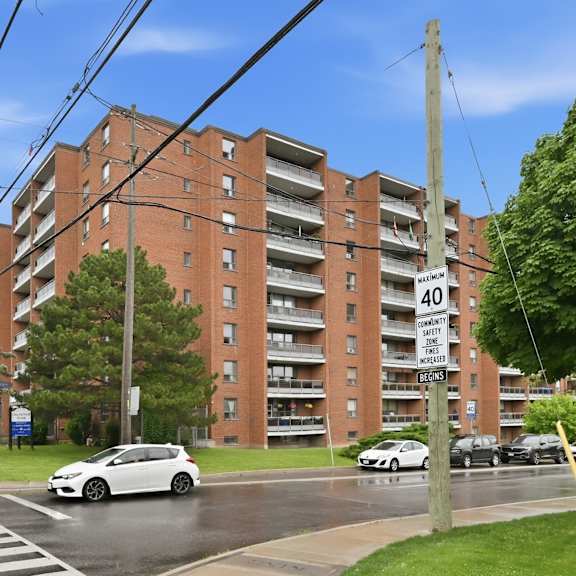 a street view of a residential building with cars parked on the side of the road.