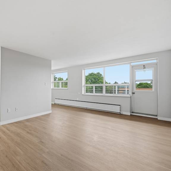 a spacious room with wooden floors and white walls.