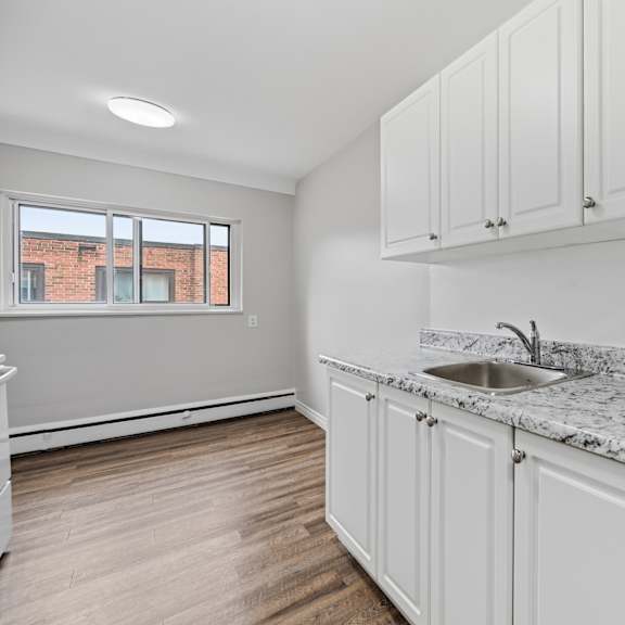 a kitchen with white cabinets and a marble countertop.
