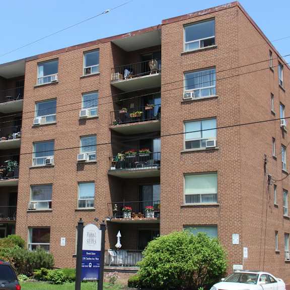 a large brick building with balconies and cars parked in front.