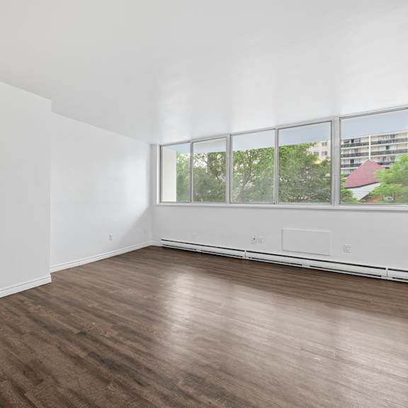 a room with white walls and wooden flooring with a window.