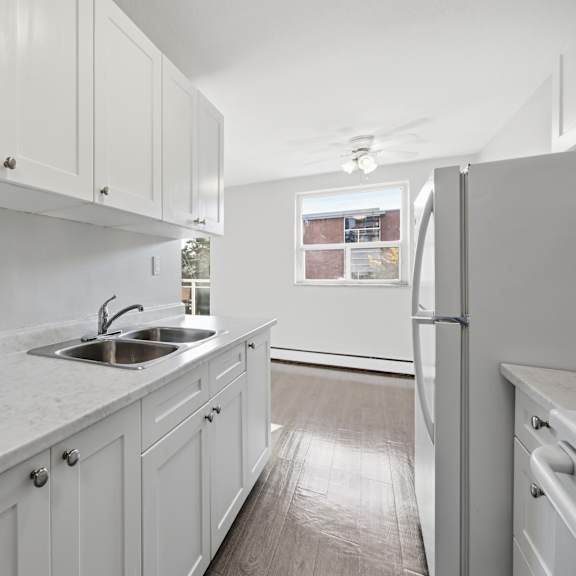 a kitchen with white cabinets and a marble countertop.