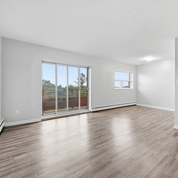a spacious room with wooden flooring and a large window.