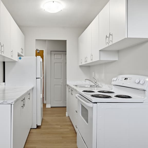 a white kitchen with a stove, oven, and refrigerator.