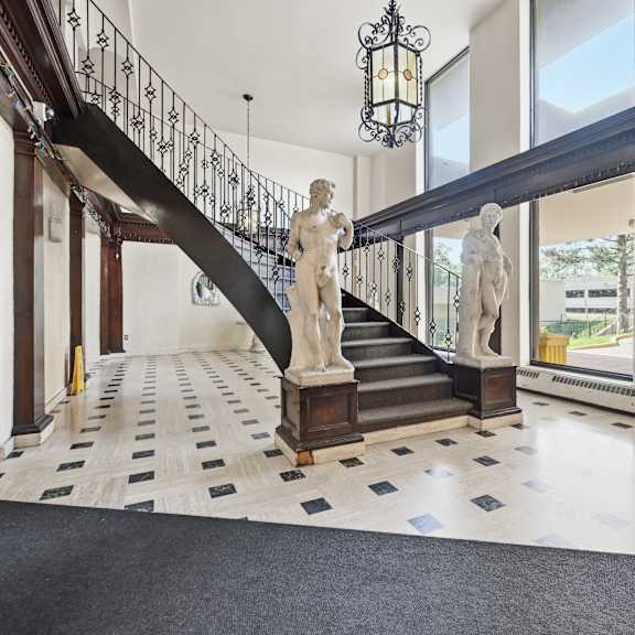 a marble statue stands on a staircase with a black railing.