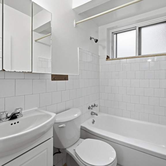 a white bathroom with a toilet, sink, and bathtub.