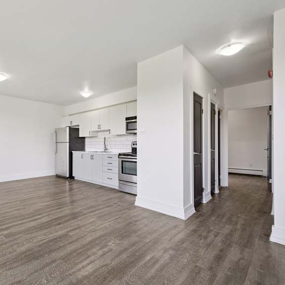 a spacious kitchen with white cabinets and a wooden floor.