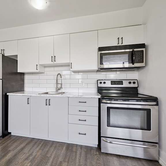 a kitchen with a stainless steel refrigerator, microwave, oven, and sink.