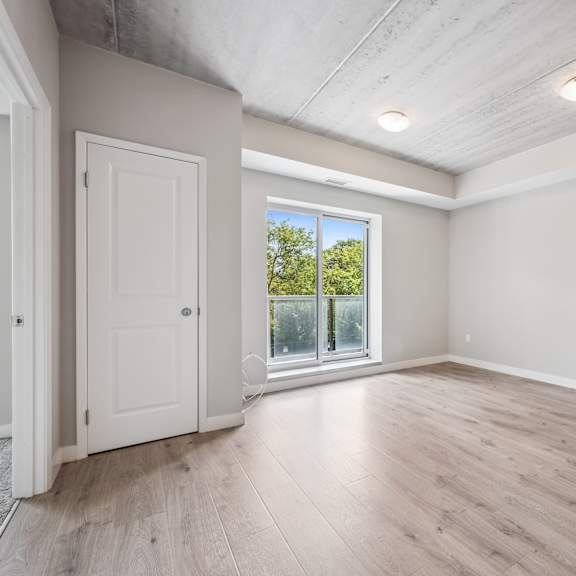 a room with a white door and a window with a view of trees.