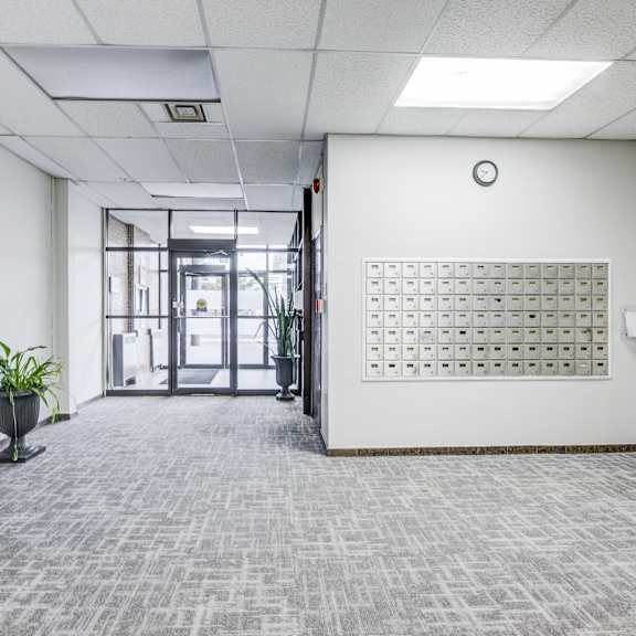 a hallway with a carpeted floor, a white wall, and a calendar on the wall.