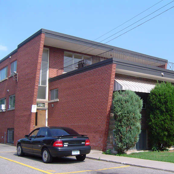 a black car is parked in a parking space in front of a red brick building.