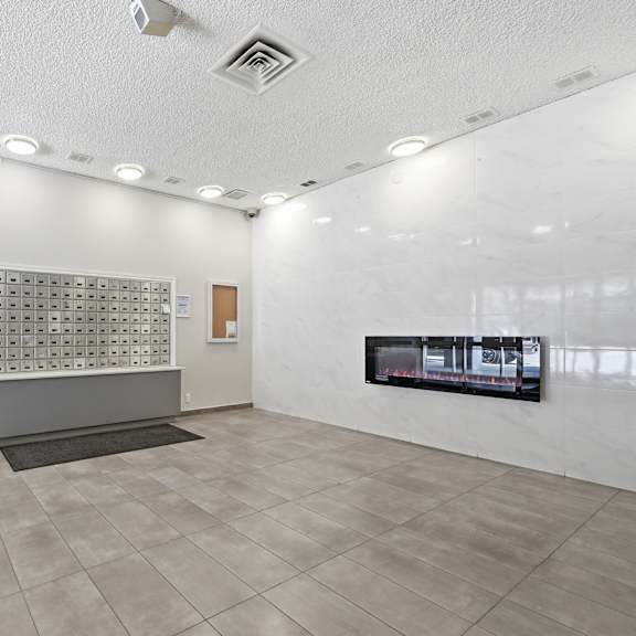 a white room with a grey carpet and a black trash can.