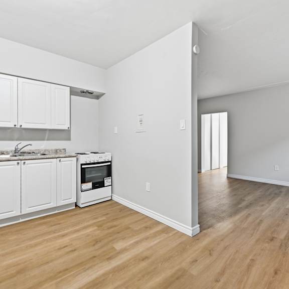 a kitchen with white cabinets and a wooden floor.