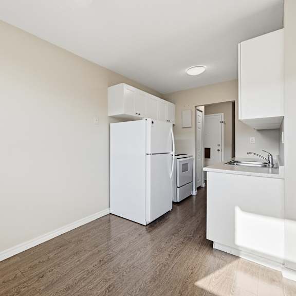 a kitchen with white appliances and wooden floors.
