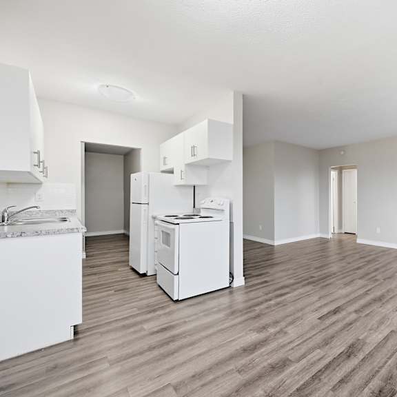 a kitchen with white appliances and wooden floors.