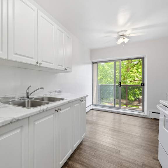 a kitchen with white cabinets and a marble countertop.