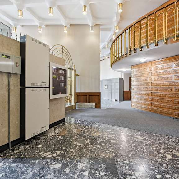 a large, empty lobby with a marble floor and a wooden staircase.