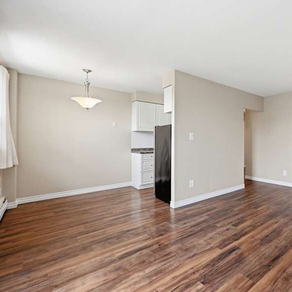 a room with wooden floors and a black refrigerator.