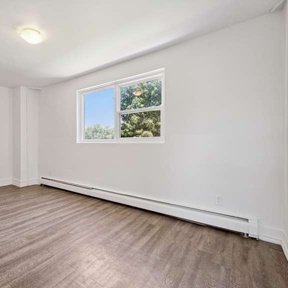 a room with a window showing a view of trees and sky.