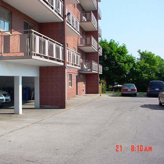 a parking lot in front of a red brick building with cars parked.