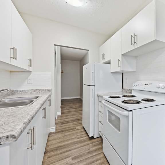 a white kitchen with a stove top oven and a sink.
