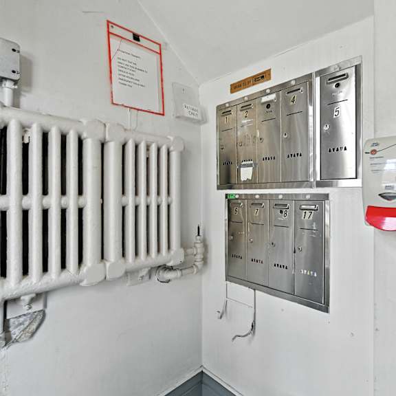 a white radiator is on the wall next to a metal electrical box.