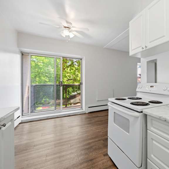 a white kitchen with a stove and a fan.