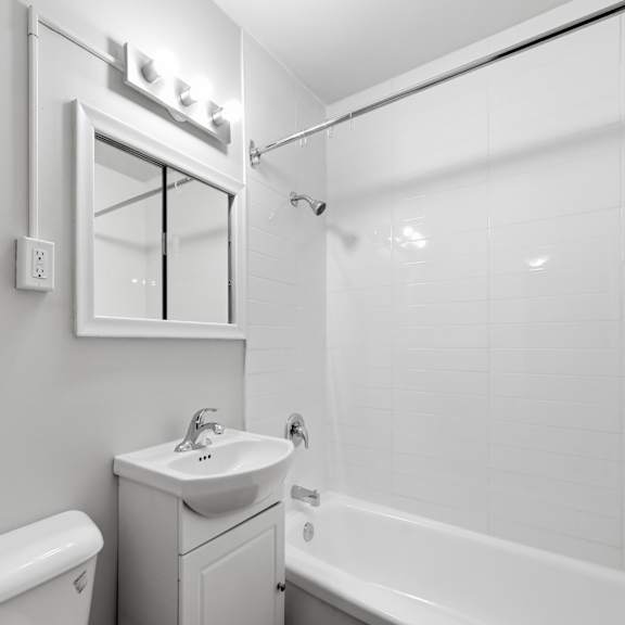 a white bathroom with a toilet, sink, and bathtub.