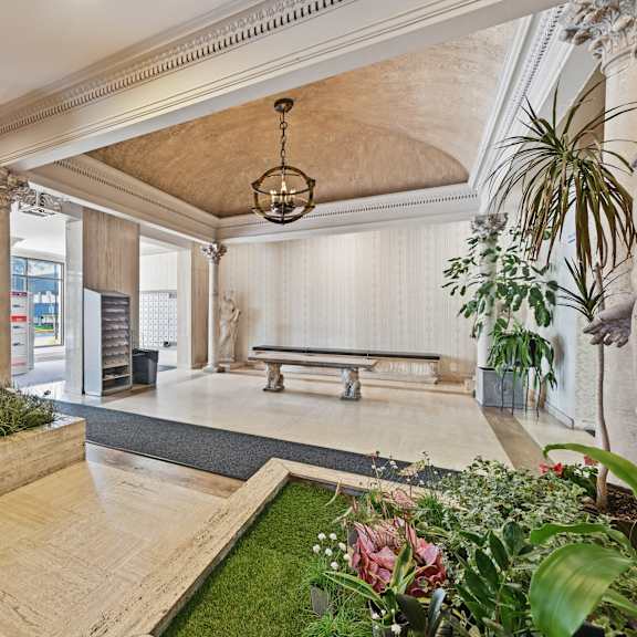 a room with a statue, a bench, and a planter with flowers.
